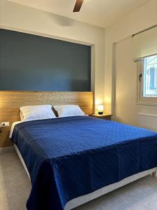 a bedroom with a large bed with a blue blanket at Sunny flat among olive trees, next to the beach in Módhion