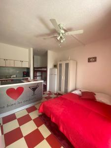 1 dormitorio con cama roja y ventilador de techo en Studio cabine + Parking : proche plage en Canet-en-Roussillon
