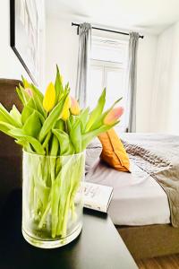 施塔德的住宿－Die Stader Oase mit Sonnenterrasse，睡床旁边的桌子上的一个郁金香花瓶
