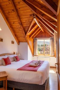 a bedroom with two beds and a large window at Hosteria y Cabañas Posada Quinen by Nordic in San Martín de los Andes