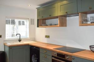 una cocina con armarios verdes y fregadero en Beautiful renovated cottage in Mersham Ashford Kent en Mersham