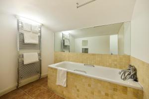 a bathroom with a tub and a large mirror at The Bayswater Gardens - Bright 3BDR Home in London