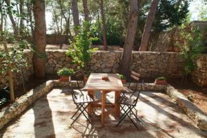 una mesa de madera con 2 sillas y una pared de piedra en Masseria Frassaniti by My Home Apulia, en Veglie