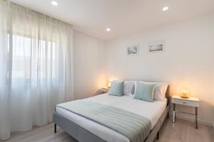 ギマランイスにあるDuke's Apartment - Guimarães Centerの白いベッドルーム(ベッド1台、窓付)