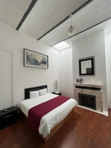 a bedroom with a large bed and a fireplace at Hotel Alhaja in Puebla