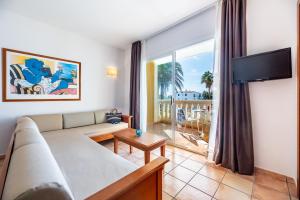 a living room with a couch and a large window at Vibra Blanc Palace Aparthotel in Sa Caleta