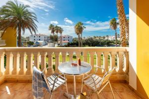 a table and chairs on a balcony with palm trees at Vibra Blanc Palace Aparthotel in Sa Caleta +22 photos