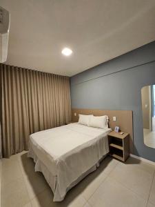 - une chambre avec un grand lit et une table de nuit dans l'établissement Aero Hotel, à Lauro de Freitas