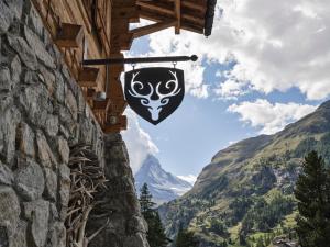 a sign hanging from a building with a view of a mountain at CERVO Mountain Resort in Zermatt