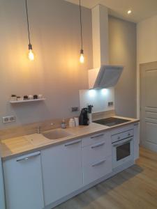 uma cozinha com armários brancos, um lavatório e luzes em Gîte des Allas em Campagne