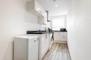 Contemporary Budget 1 Bed Apartment in Central Doncaster في دونكاستير: مطبخ أبيض مع حوض وثلاجة