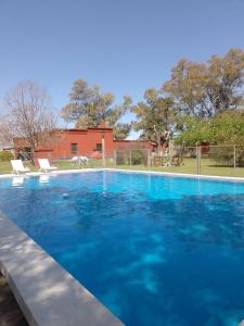 une grande piscine bleue avec deux chaises blanches dans l'établissement La mancha verde casa de campo, à Capitán Sarmiento