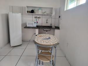 uma cozinha com um banco, uma mesa e um frigorífico em Aldenora Flats em Fortaleza