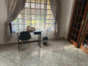 einen Tisch und einen Stuhl in einem Zimmer mit Fenster in der Unterkunft Erima Lodge in Johannesburg