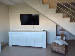 - un salon avec une télévision et une armoire blanche dans l'établissement Apartamento Panoramica Golf, à Sant Jordi