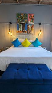a bedroom with a large bed with blue and yellow pillows at Maloka Boutique Hostel in Cartagena de Indias