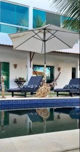 a pool with a table and an umbrella next to a building at Pousada De Bona Studio's in Pôrto de Pedras