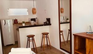 a kitchen with two bar stools and a refrigerator at Pousada De Bona Studio's in Pôrto de Pedras