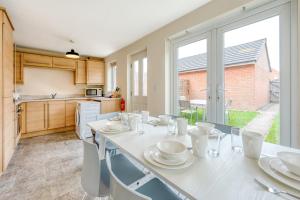 uma cozinha com uma mesa branca com cadeiras e uma janela em Spectacular House with Parking em Chorley