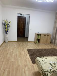 een woonkamer met een bank en een vaas met bloemen bij Apartament central in Râmnicu Vâlcea