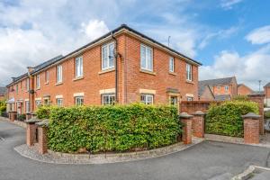 una casa di mattoni con una siepe davanti di Spectacular House with Parking a Chorley