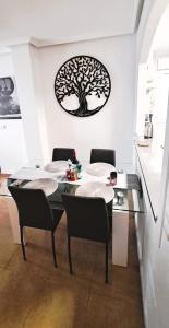 a dining room with a table with chairs and a tree on the wall at Apartament Julia de LUX in Torrevieja