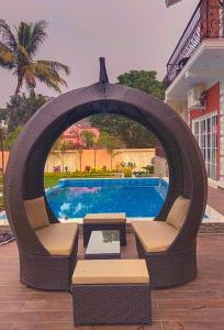 a wicker swing with chairs and a swimming pool at Chaitali The Villa in Shānti Niketan