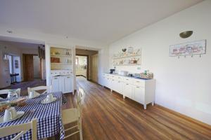 uma cozinha com armários brancos, uma mesa e uma sala de jantar em La Corte di Nonna Gemma - Holiday Home em Delebio