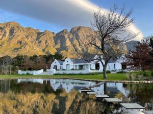 a house next to a lake with mountains in the background at Chambray Estate - The Terraces in the Vines in Franschhoek