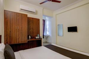 een slaapkamer met een bed, een kast en een tv bij OYO Flagship 35467 Shiridi Residency Near Birla Mandir in Hyderabad