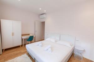 a white bedroom with a white bed and a desk at Santa Maria Novella Apartment in Florence