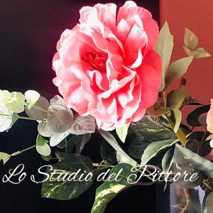 a pink flower in a vase with some leaves at Lo Studio del Pittore in Vasto