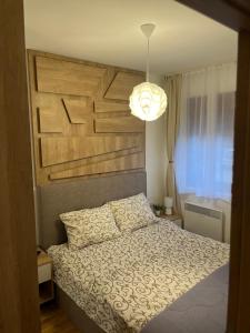 a bedroom with a bed with a large wooden headboard at Apartman i spa Marko Zlatibor in Zlatibor