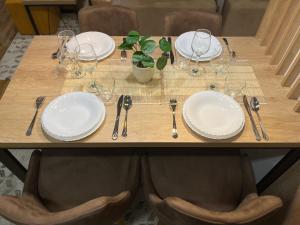 una mesa de madera con platos y utensilios. en Apartman MM Zlatibor en Zlatibor