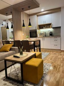 Apartman MM Zlatibor في زلاتيبور: غرفة معيشة مع أريكة وطاولة ومطبخ
