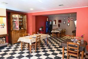 a restaurant with tables and chairs and red walls at Le Relais du Coustoubi in Campouriez