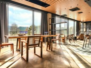 jadalnia ze stołem i krzesłami oraz dużymi oknami w obiekcie Happy Valley Resort Szklarska Poręba w Szklarskiej Porębie