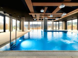 a large swimming pool with blue water and windows at Happy Valley Resort Szklarska Poręba in Szklarska Poręba