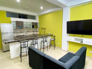 - une cuisine avec un canapé et un bar avec des tabourets dans l'établissement Hospedaje Rocio del Mar, à Cerro Azul