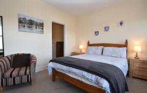 a bedroom with a large bed and a chair at Tilling View with private parking in Rye