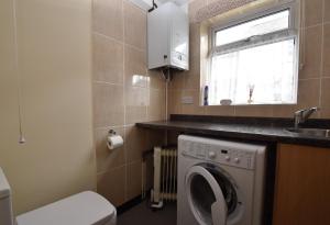 a small bathroom with a washing machine in it at Tilling View with private parking in Rye