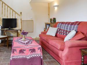 a living room with a red couch and a table at Hafotty Fach in Llanfyllin