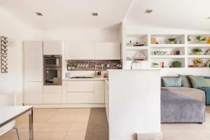 cocina y sala de estar con armarios blancos y cama en Ognina view house en Catania