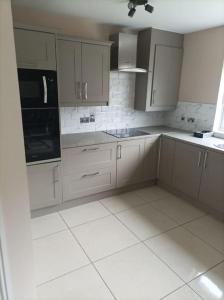 uma cozinha com armários brancos e electrodomésticos pretos em Iacomm Lucan 3 bed em Lucan