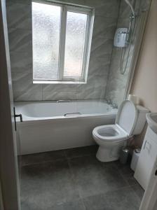 uma casa de banho com uma banheira, um WC e uma janela. em Iacomm Lucan 3 bed em Lucan