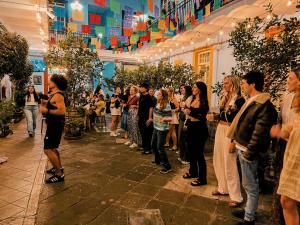a crowd of people standing in a room with plants at Viajero CDMX Centro Hostel in Mexico City