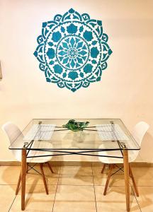 una mesa de cristal con 2 sillas y un mandala azul en una pared en Mandalas 1, amplio apartamento en Belén de Escobar