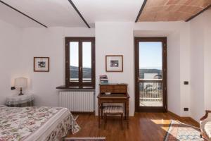 a bedroom with a bed and a desk and windows at Private Estate Among the Vineyards of Alba - Italy in Trezzo Tinella