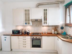 a white kitchen with white cabinets and a microwave at Il Nido sullo Scoglio in Bonassola