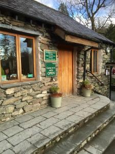 a stone building with potted plants in front of it at Gerdy Shepherd's Hut in Rydal